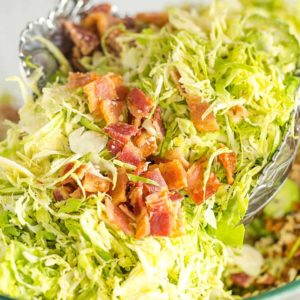 Tossing brussels sprouts salad with bacon, pecans and Parmesan cheese.