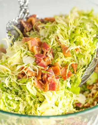 Tossing brussels sprouts salad with bacon, pecans and Parmesan cheese.