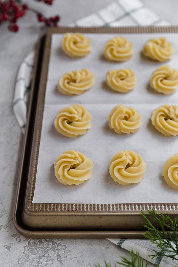 Danish butter cookies piped onto parchment paper, ready to be baked.