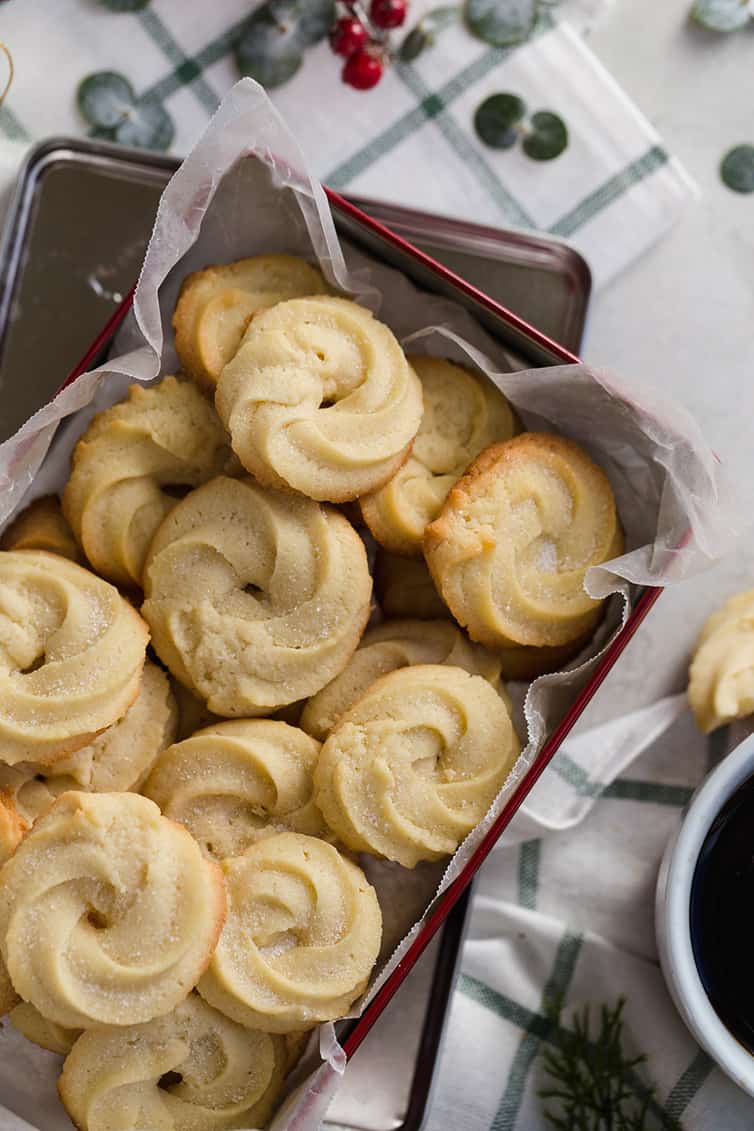 A batch of Danish butter cookies in a parchment-lined tin.