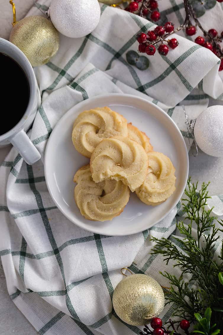 A plate of Danish butter cookies next to a cup of coffee.