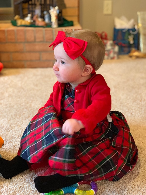 Isabelle sitting on the floor in her Christmas dress.