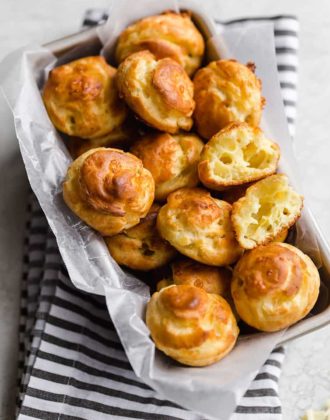 A basket full of gougeres with one split in half.