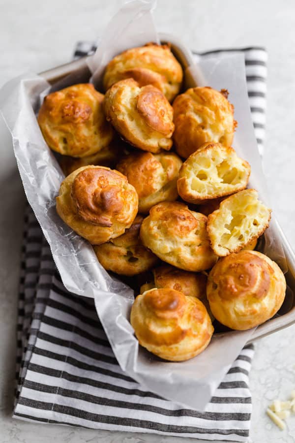 A basket full of gougeres with one split in half.