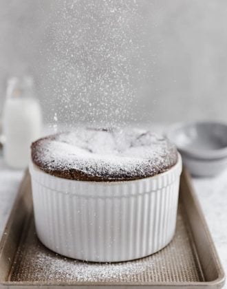 A chocolate souffle with powdered sugar being sprinkled on top.