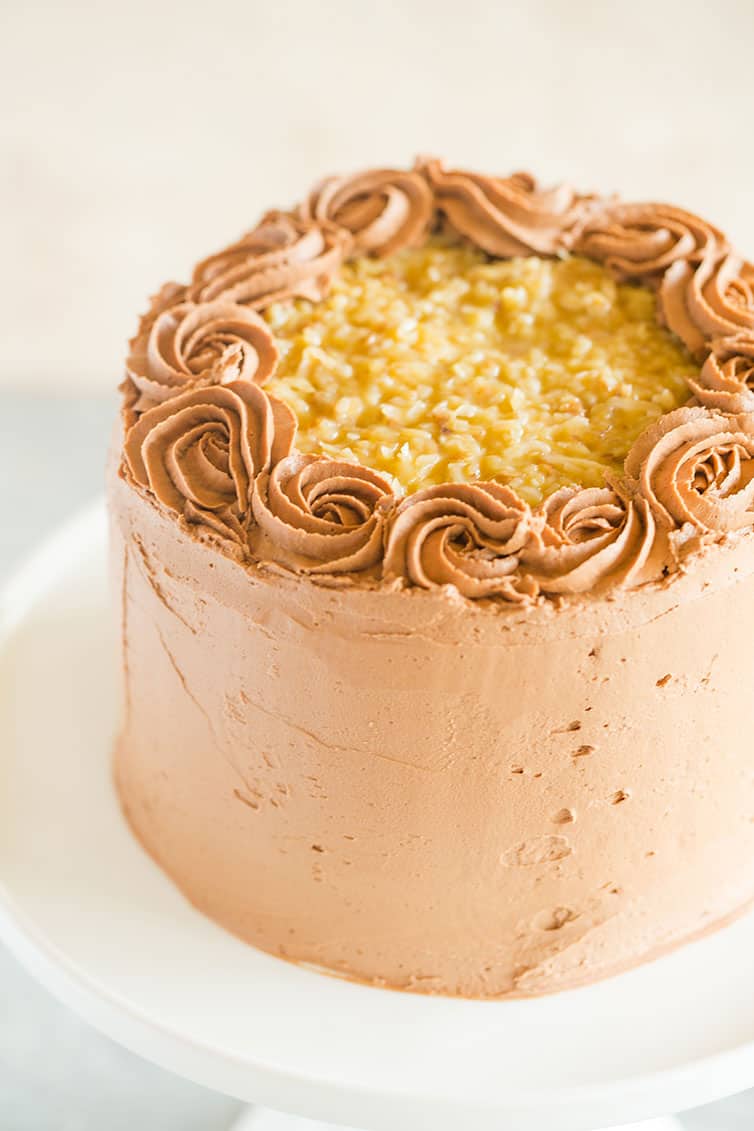 German chocolate cake on a white pedestal cake plate.