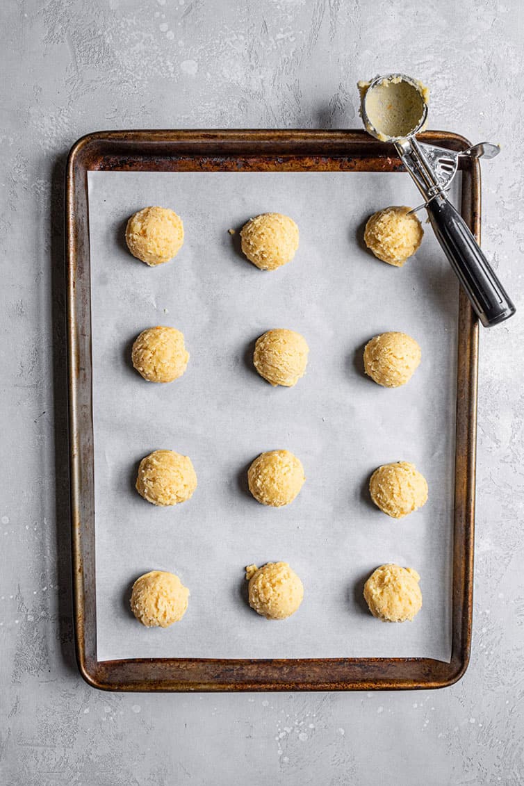 A cookie sheet with balls of orange cookie dough.