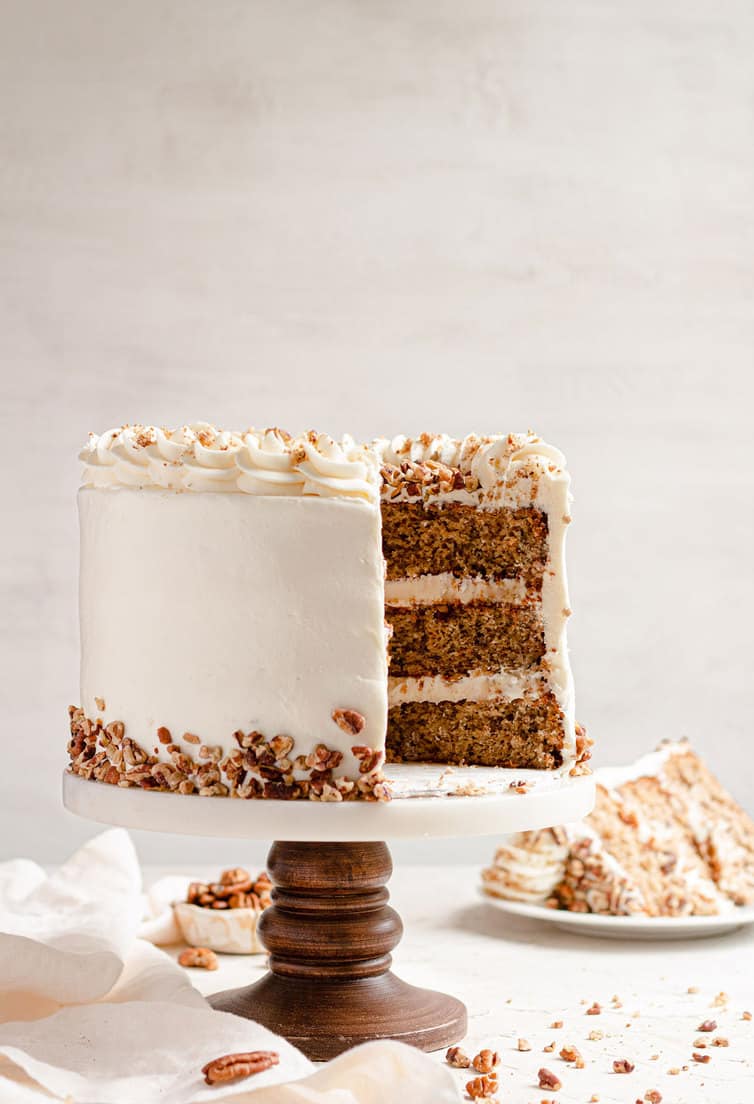 A hummingbird cake on a cake pedastal with slices removed.