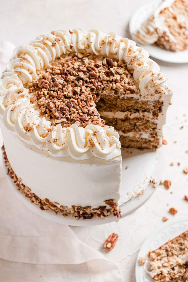 An overhead photo of hummingbird cake cut into, with pecans on top.