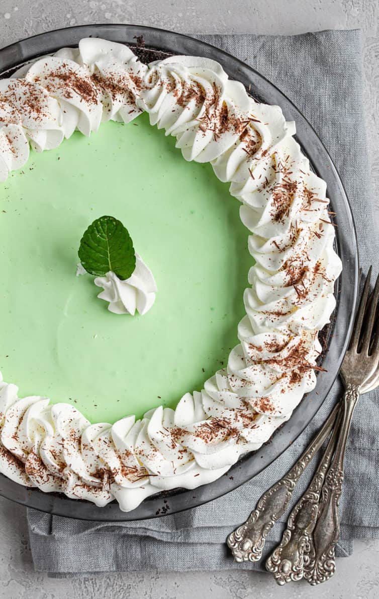 An overhead photo of grasshopper pie with whipped cream around the border.