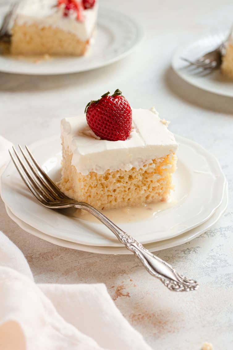 A piece of tres leches cake on a plate with a fork.