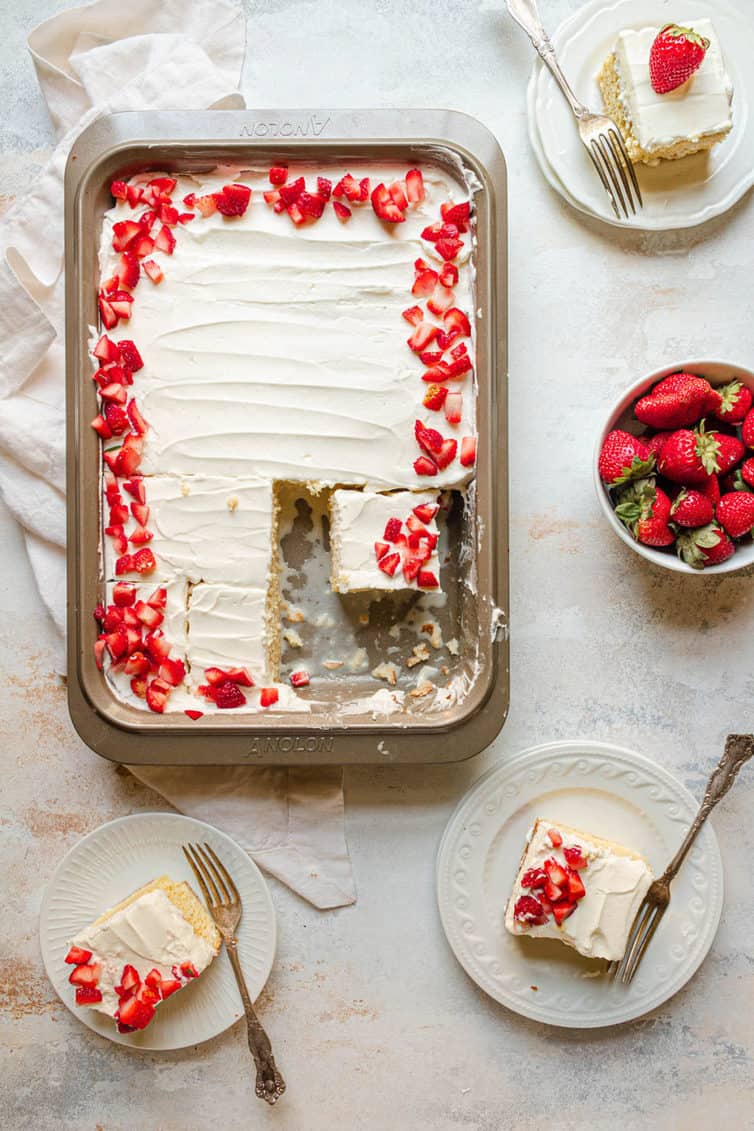 A pan of tres leches cake with three pieces removed and on plates.
