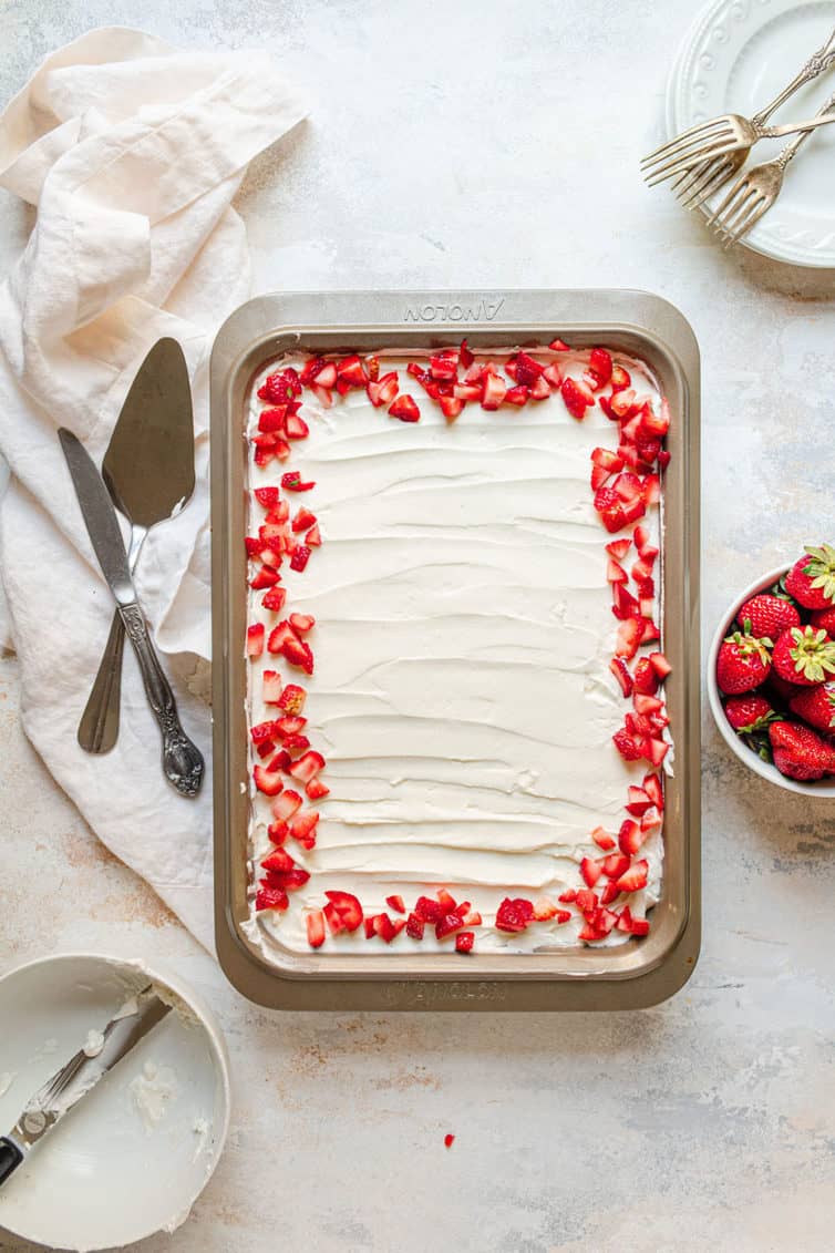 Pan of tres leches cake with strawberries around the border.