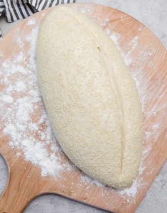 Loaf of Italian bread on a wooden peel before baking.