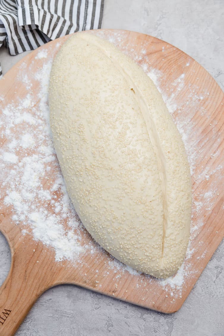 Loaf of Italian bread on a wooden peel before baking.