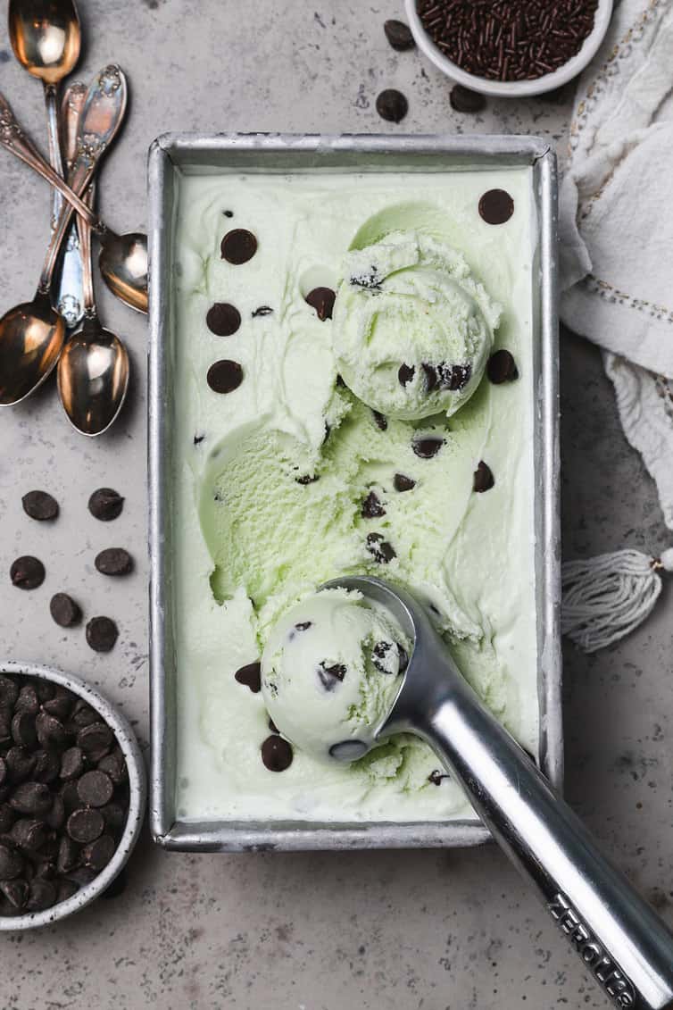 Mint chocolate chip ice cream in a loaf pan with scoops coming out.