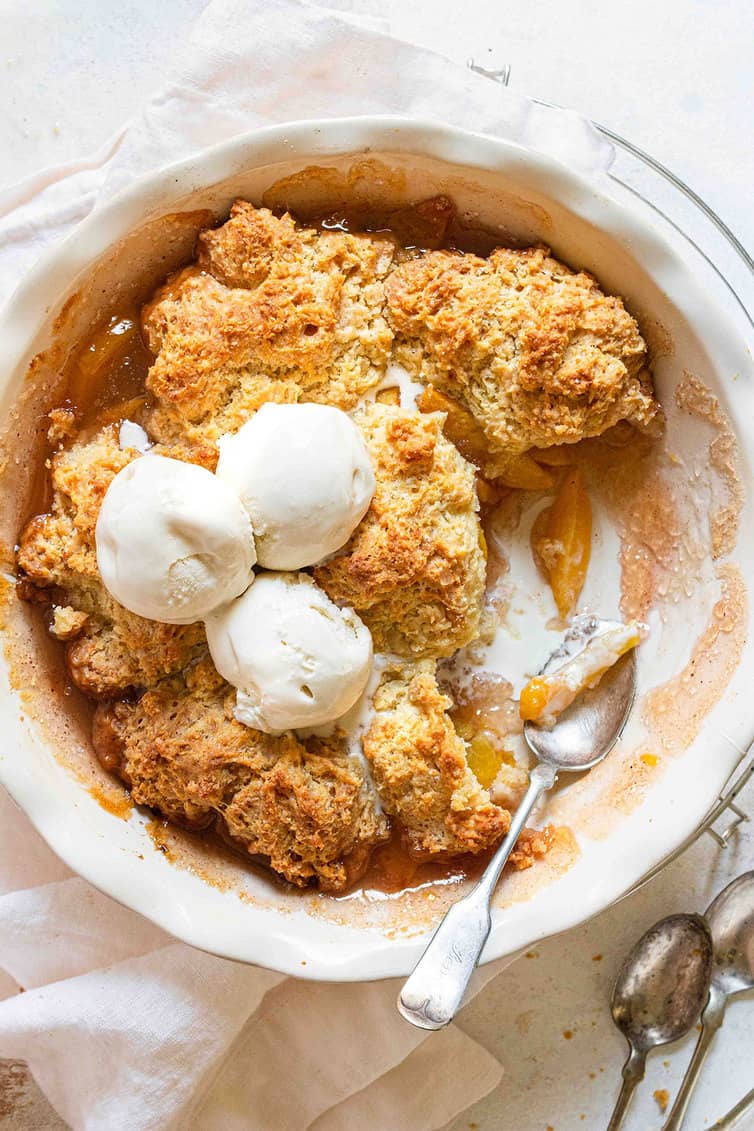 Peach cobbler in a pan with a large serving taken out.
