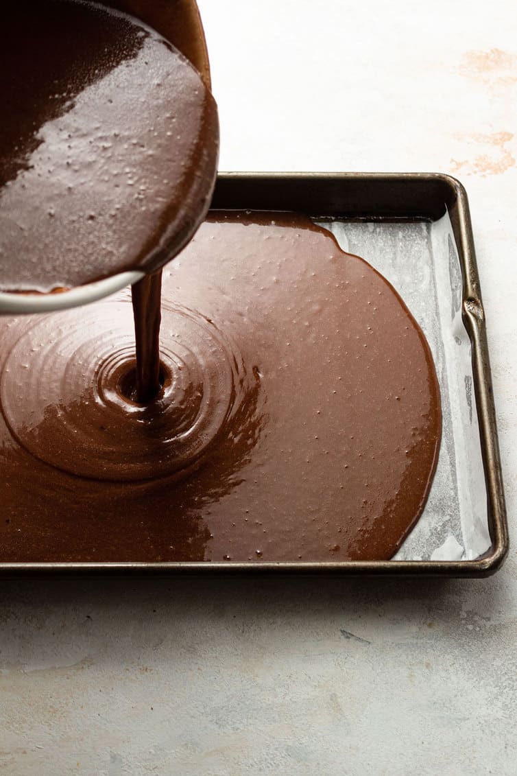 Pouring cake batter into a sheet pan.