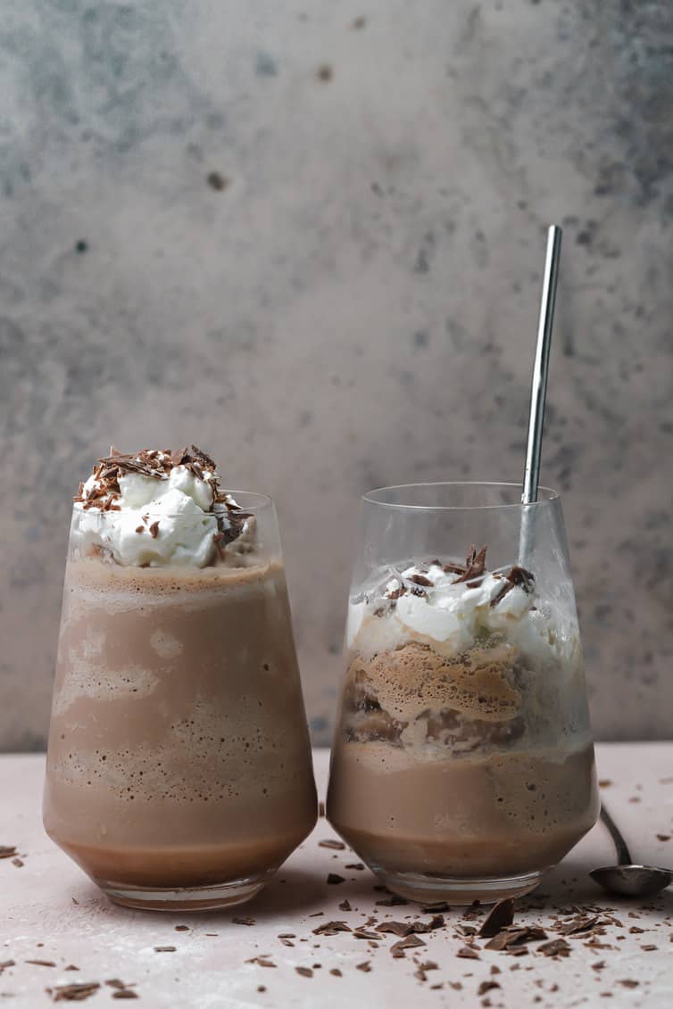 Two glasses of frozen hot chocolate, one half drank with a spoon in the glass.