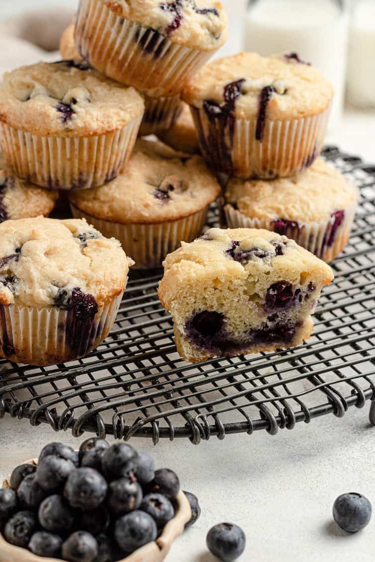 A blueberry muffin cut in half on a cooling rack.