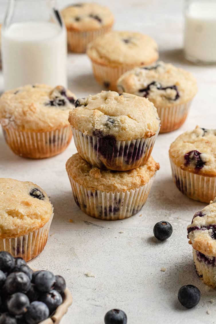 Two blueberry muffins stacked on top of each other with others in the background.