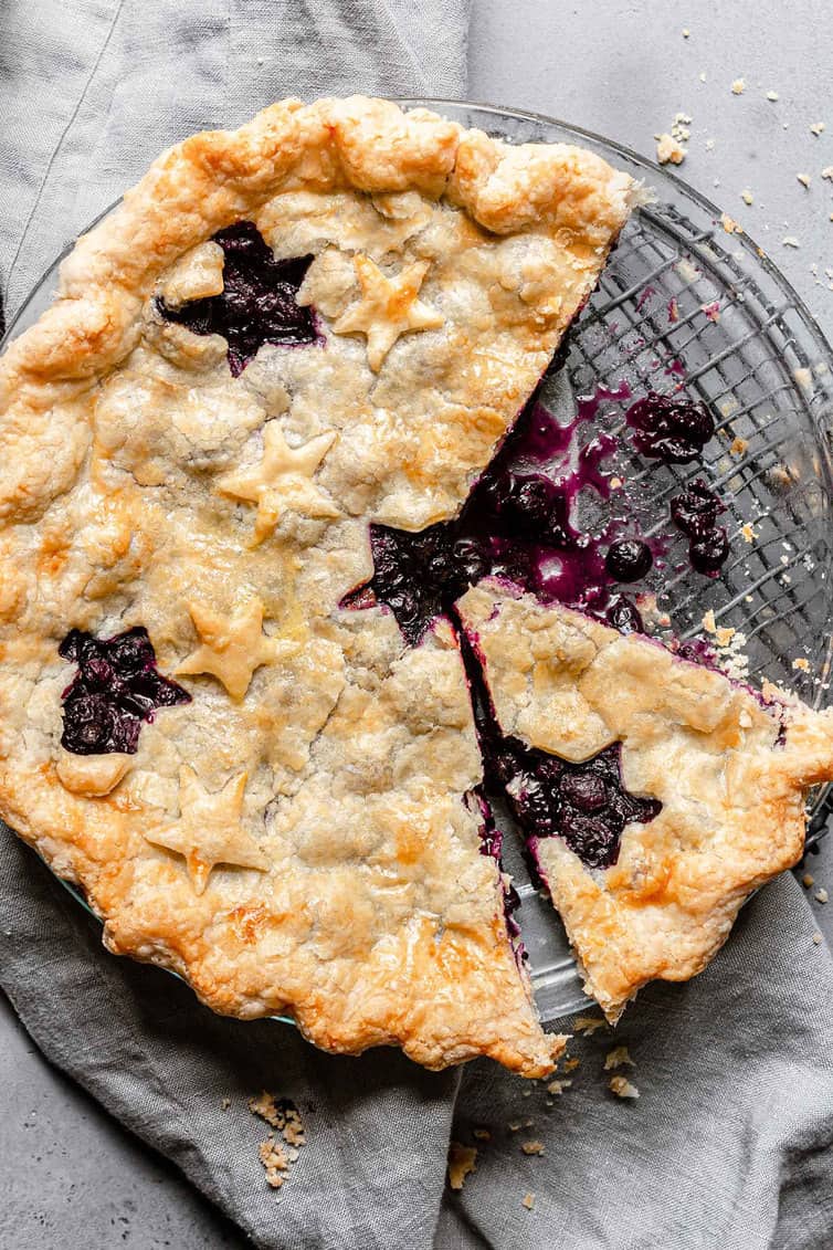 Overhead photo of blueberry pie with slice taken.