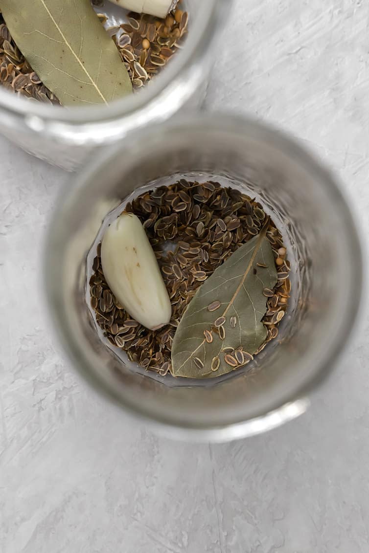 Dill seed, bay leaves and garlic clove in the bottom of a jar.