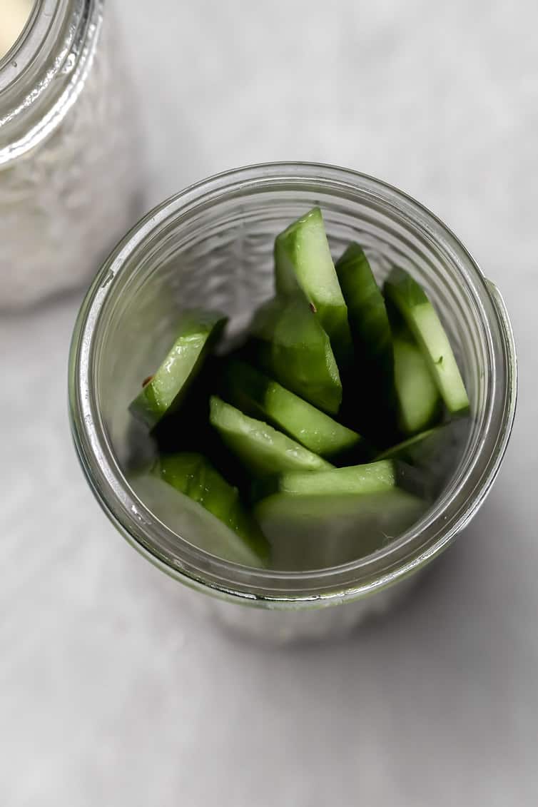 Cucumbers packed into a glass jar.