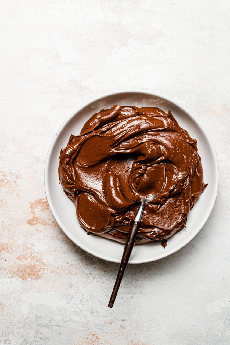 Chocolate frosting in a bowl with a spoon.