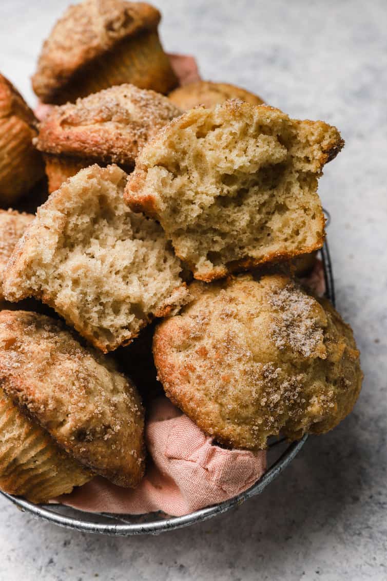Basket of apple muffins with one broken in half.
