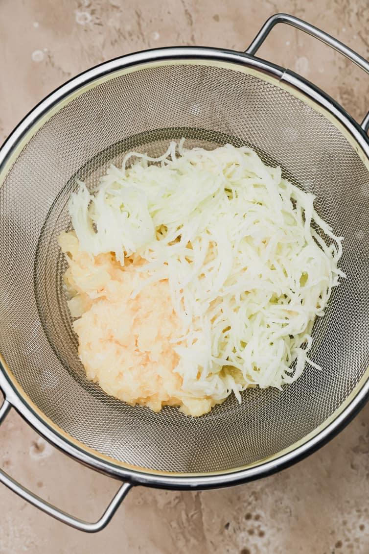 Shredded apple and crushed pineapple in colander.