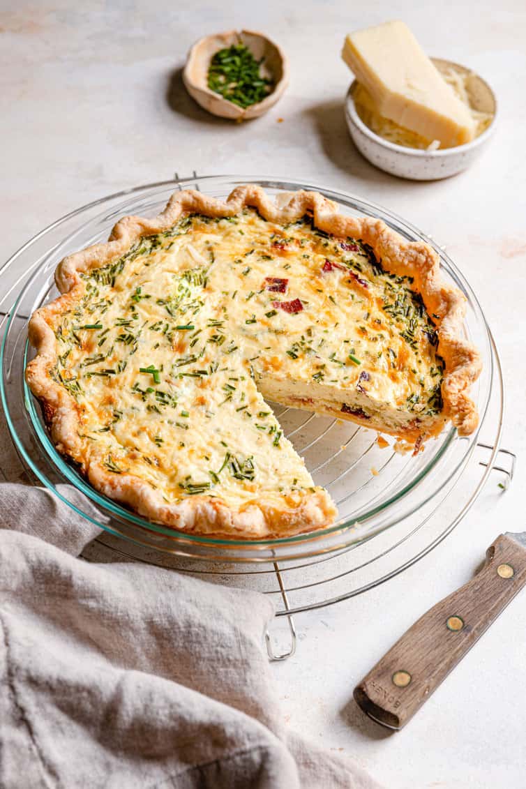 Quiche Lorraine in pie plate with a slice removed.