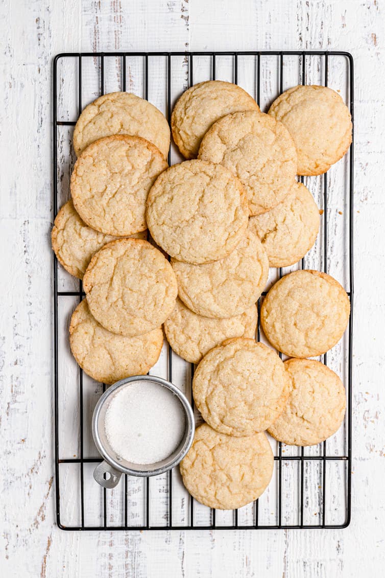 Sugar cookies on a wire rack with a bowl of sugar.