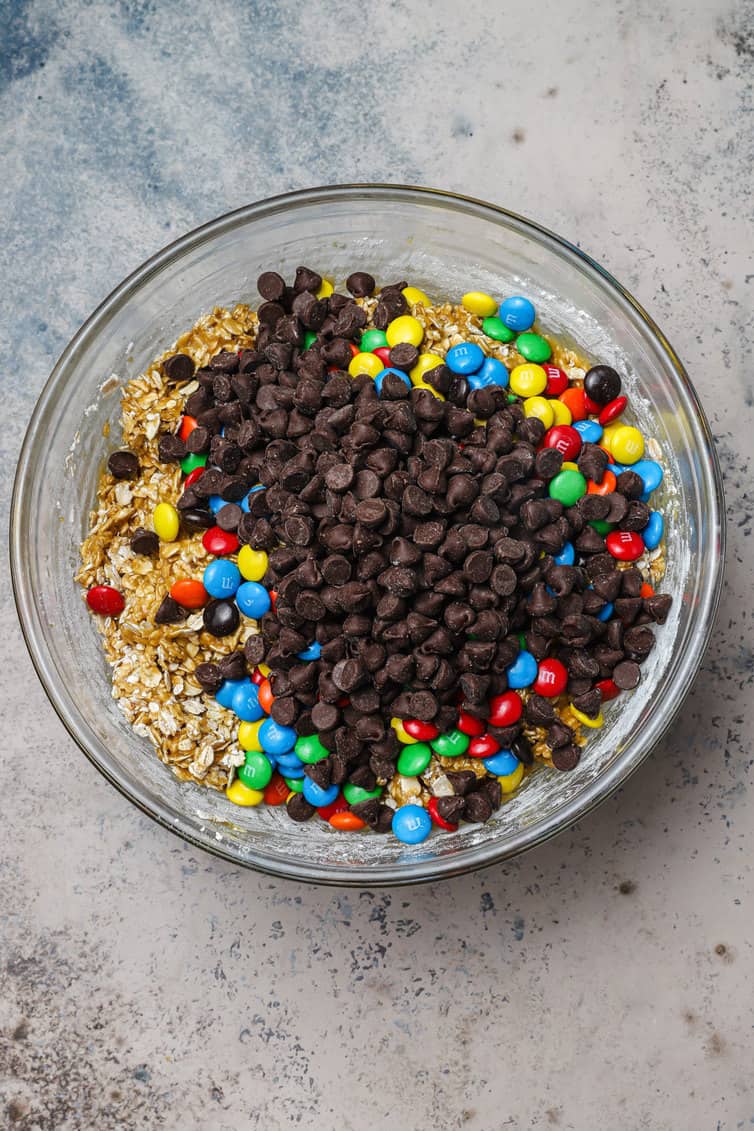 Chocolate chips and M&Ms in bowl of cookie batter.