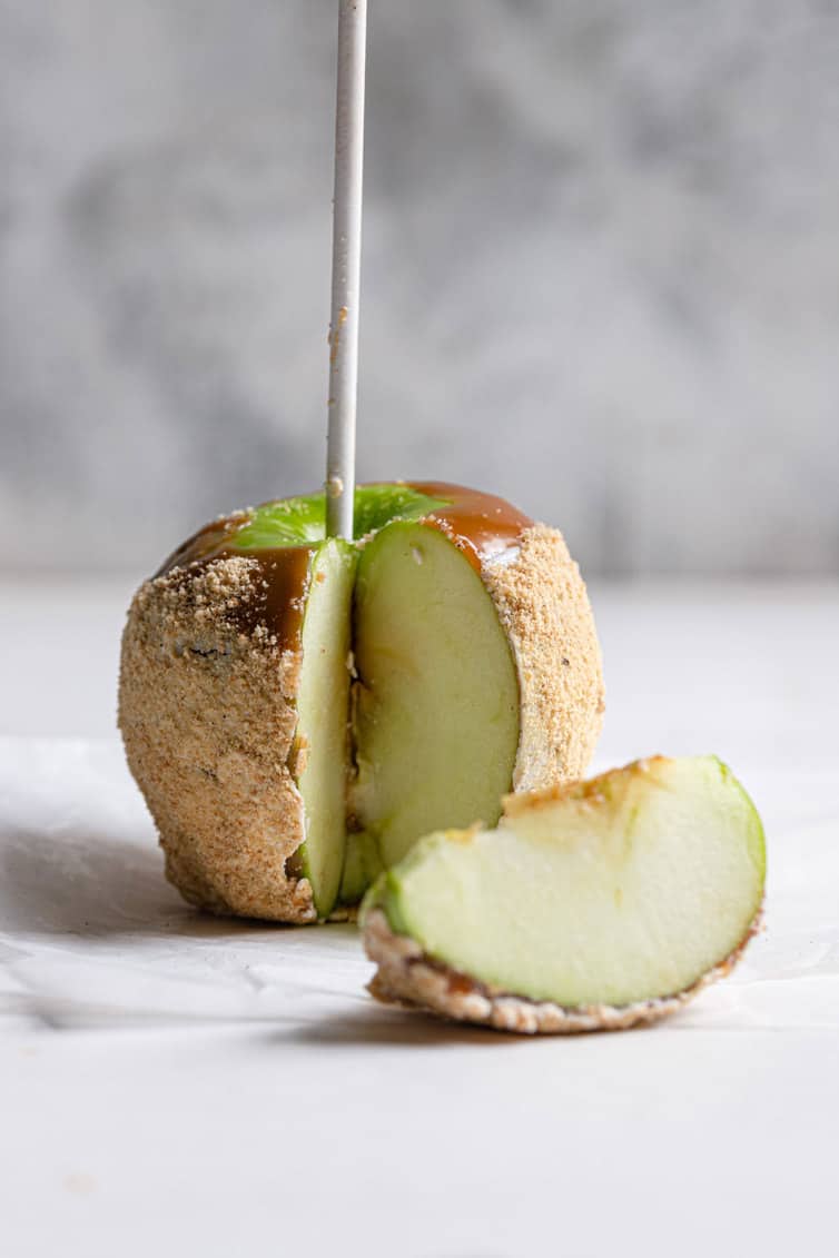 A garnished caramel apple with a slice cut out of it.
