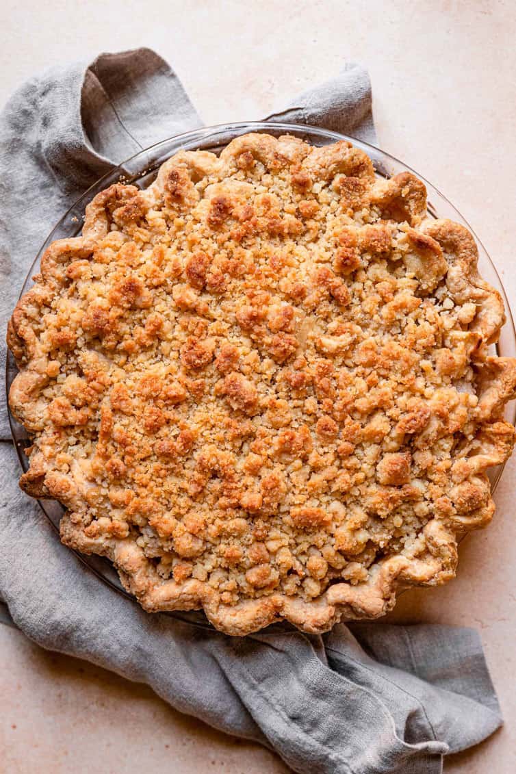 Overhead photo of Dutch apple pie with linen napkin underneath pie plate.