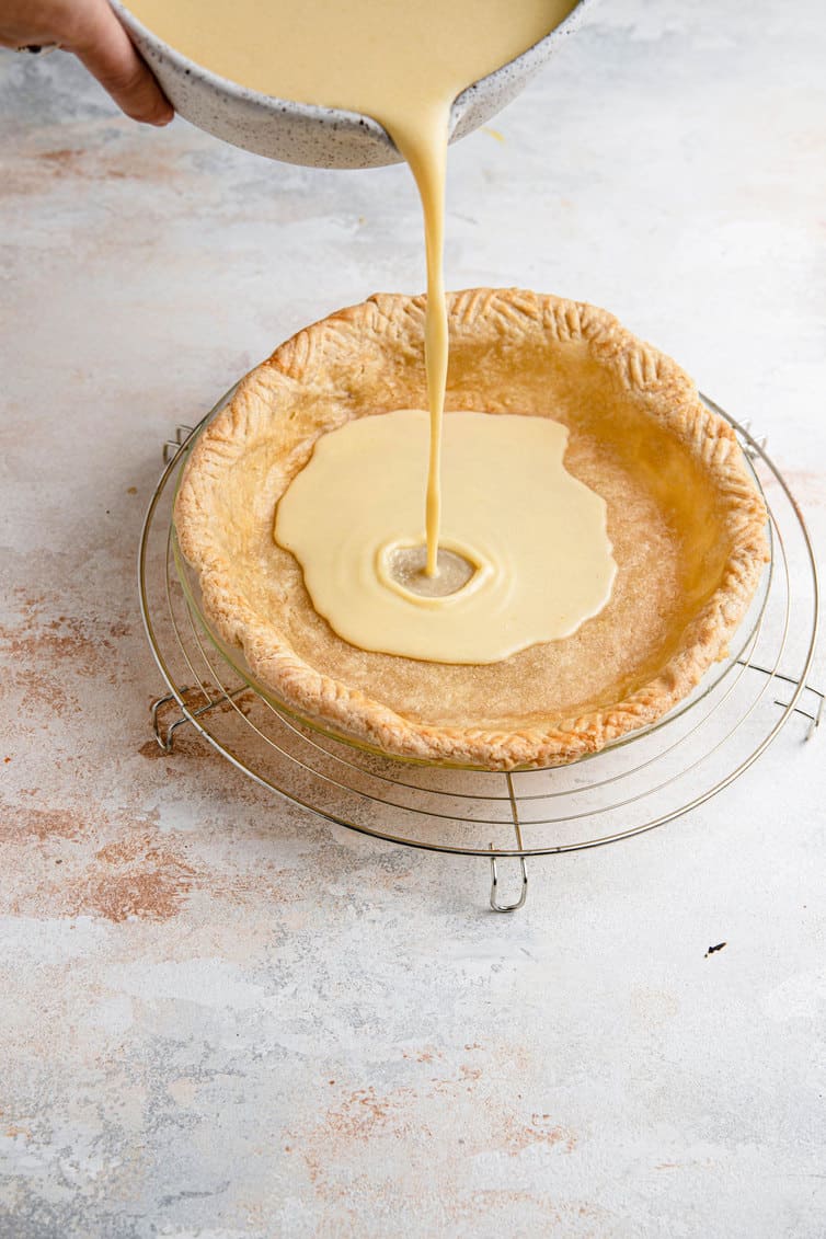 Pouring buttermilk pie filling into crust.