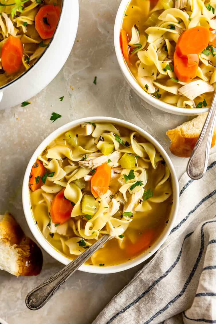 A bowl of chicken noodle soup with a spoon.
