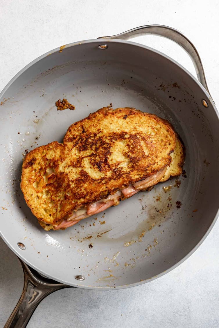 A Monte Cristo sandwich being fried in a skillet.