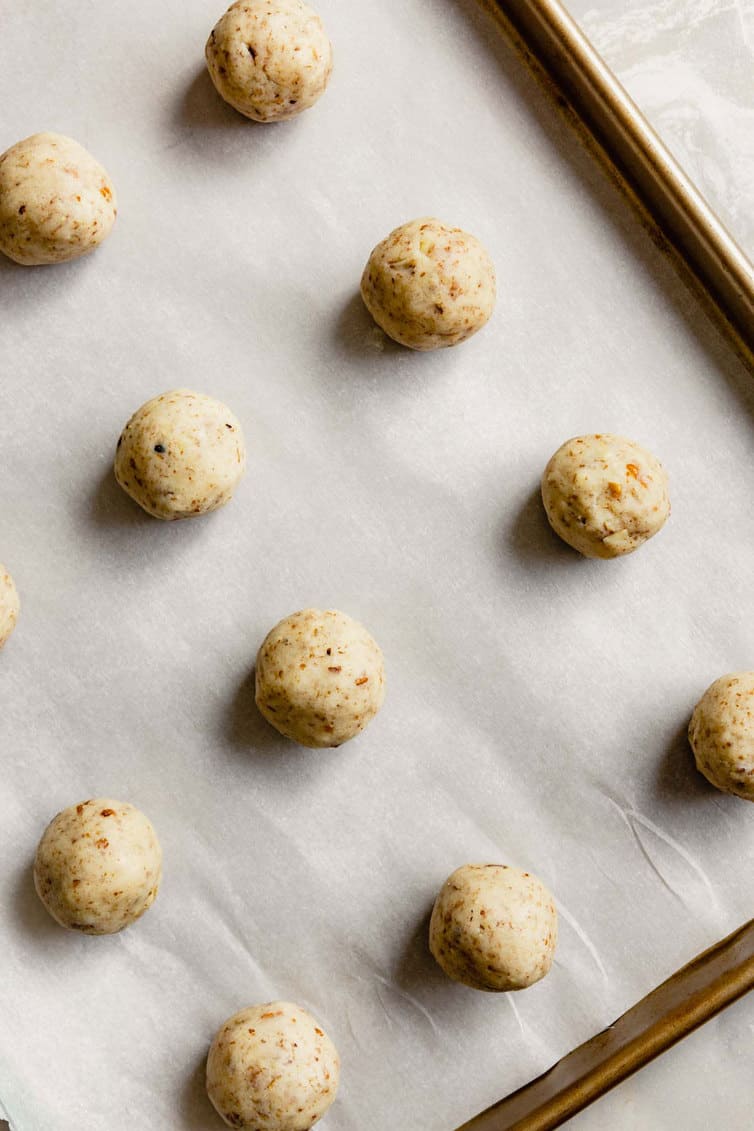 Snowball cookie dough rolled in balls on a parchment-lined sheet.