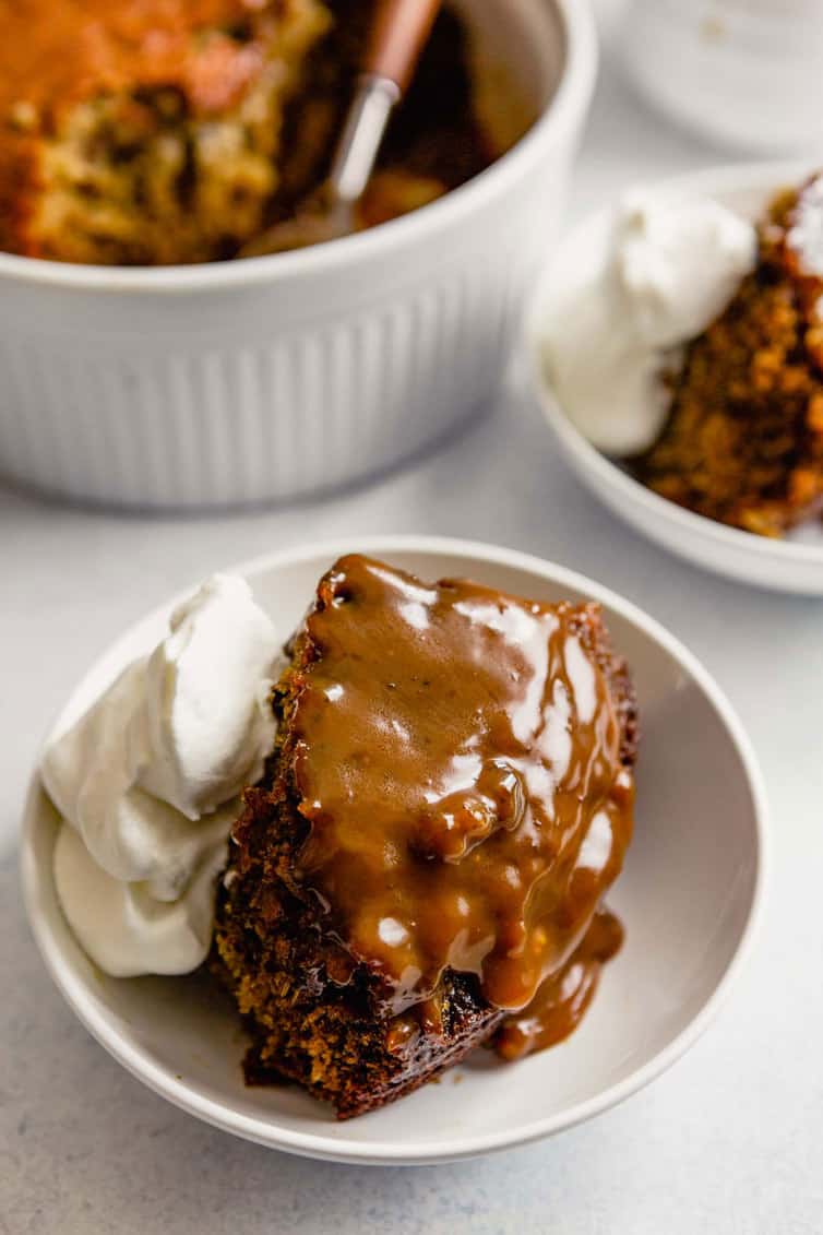 Sticky Toffee Pudding in a bowl with whipped cream.
