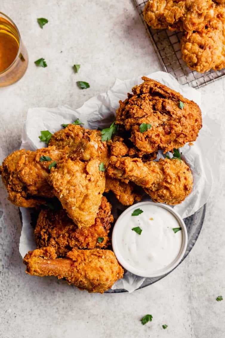 A pan of crispy buttermilk fried chicken with a small ranch dipping cup.