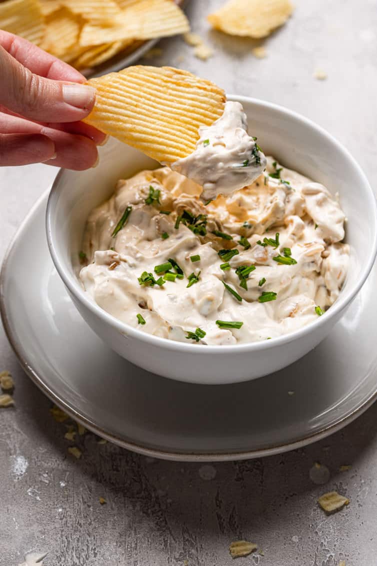 A potato chip dipping into homemade French onion dip.