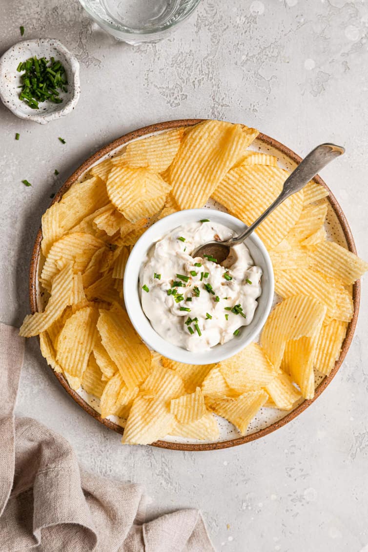 A bowl of onion dip surrounded by potato chips.
