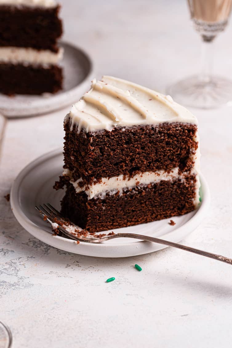 A slice of Guinness chocolate cake with a bite out on a white plate with a spoon in front.