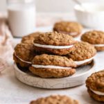 A square picture with a white plate piled up with 4 oatmeal cream pies.