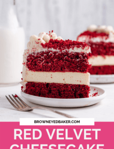A slice of red velvet cheesecake on a small white plate with a fork in front and a jug of milk to the back left with a pink rectangle at the bottom and the words red velvet cheesecake in white.