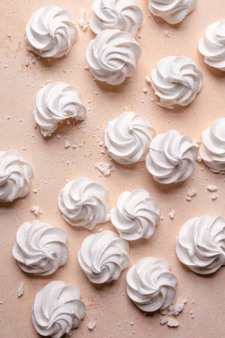 Crisp white meringue cookies on a pink counter.