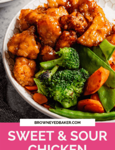 A bowl of sweet and sour chicken with stir-fry vegetables in a white bowl with a pink rectangle at the bottom that says sweet and sour chicken.