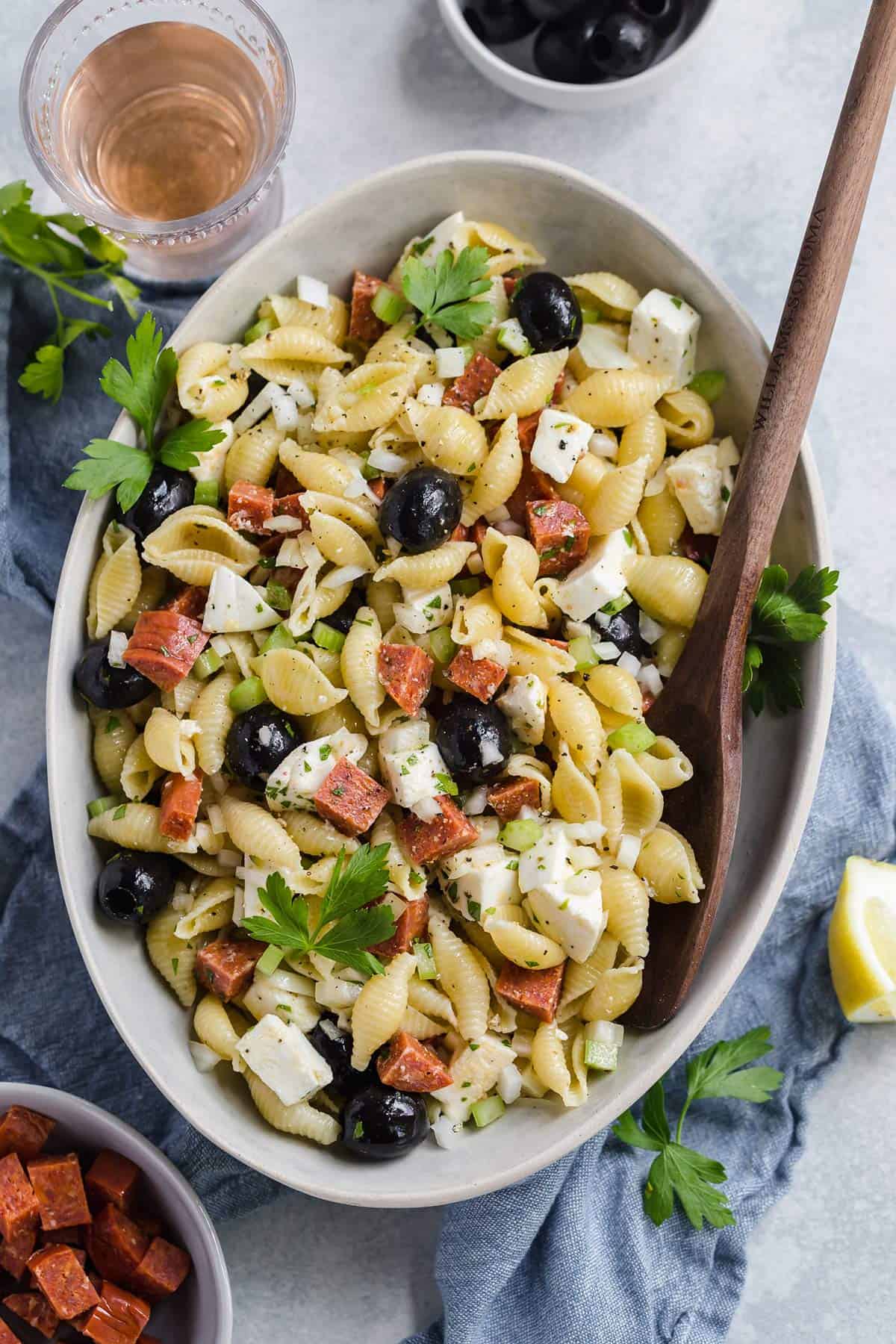 Bowl of pasta salad with glass of wine next to it.